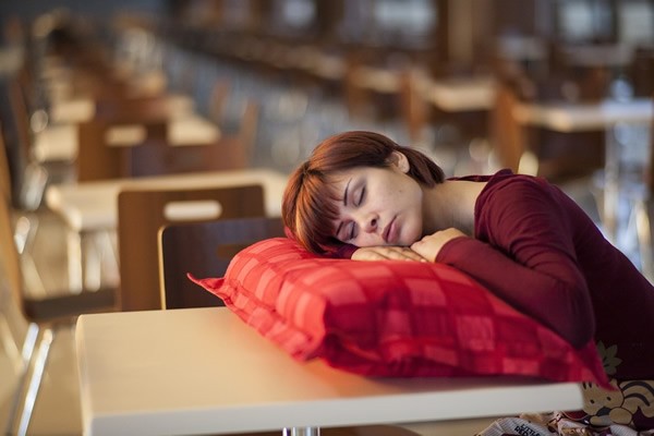 photo of woman at work laying her head on a table sleeping